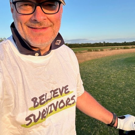 Smiling man wearing a Believe Survivors tshirt