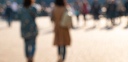A blurred image shows two unidentifiable women walking away from us down a street.