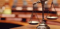 A wooden desk with a silver scale of justice on top of it against a blurred background.