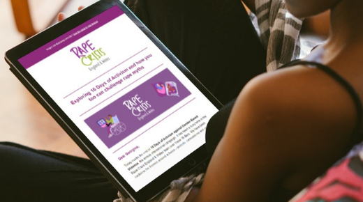A woman sits on a sofa holding an iPad. The iPad is open on the Rape Crisis England and Wales newsletter
