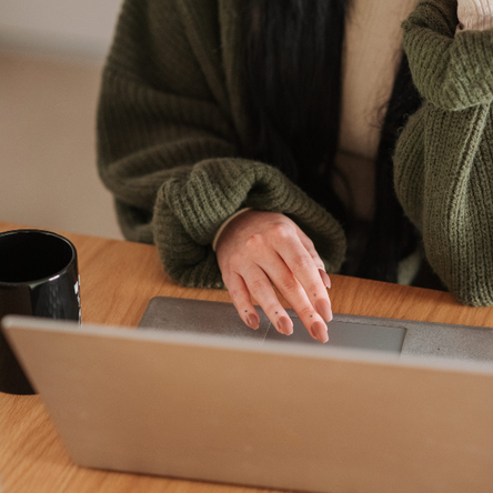 A shot of a laptop with a woman's hand scrolling on the touchpad.