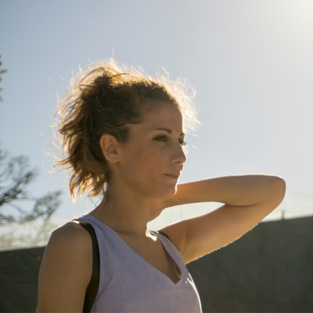 A young woman looks serious as she stands in the sunshine.